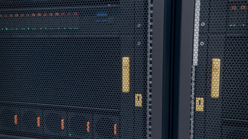 8U GPU servers seen through a perforated front door: yellow pull tabs and orange fan-module handles
